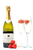 Bottle of champagne with two flutes with floating strawberries