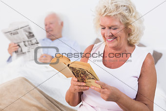 Old couple reading book and newspaper