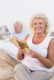 Smiling aged couple reading book and newspaper