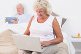 Aged couple using a tablet and the laptop