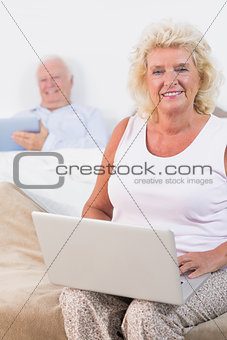 Happy aged couple using a tablet and the laptop