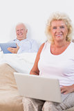Happy old couple using a tablet and the laptop