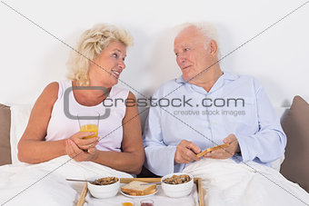 Happy aged couple eating breakfast