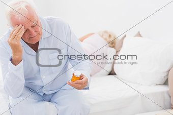 Old man looking at pills