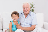 Joyful grandfather and grandson sitting on the sofa
