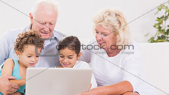 Grandparents with children using a laptop