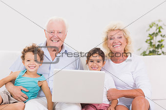 Smiling grandparents with children using a pc