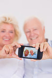 Aged couple taking pictures with smartphone
