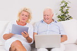 Aged couple using a laptop and the tablet
