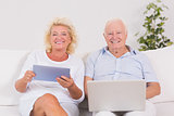 Smiling old couple using a laptop and the tablet