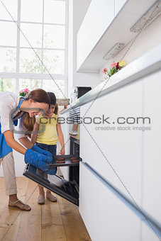 Mother taking cookies out of the oven