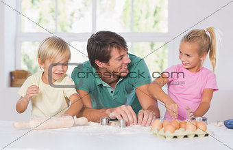 Father and his children cutting cookies out