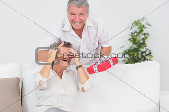 Old man hiding eyes of his wife for a gift