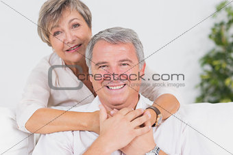 Old couple smiling at the camera and hugging