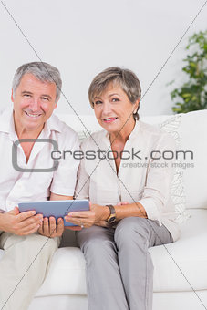 Old lovers looking camera with tablet pc