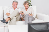Old couple watching TV with legs crossed