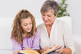 Portrait of a child and her grandmother reading a book