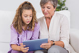 Child and her grandmother holding tablet pc