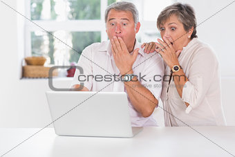 Old couple surprised in front of a laptop