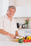 Old man smiling and chopping vegetables