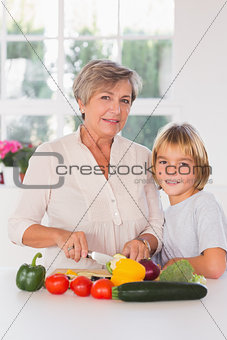 Granny cutting vegetables with her grandson