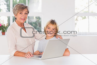 Granny and child looking camera with a laptop