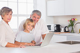Child and grandparents looking at camera with a laptop