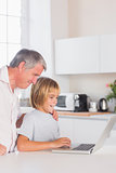 Child and grandfather looking at laptop with smile