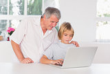 Grandfather and child looking at laptop with smile