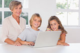 Grandmother and children looking at the camera together with laptop in front
