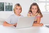 Two children looking at the camera with laptop