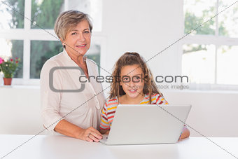 Grandmother and child looking at camera together with laptop