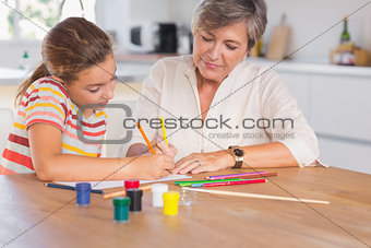 Little girl drawing with her grandmother focused