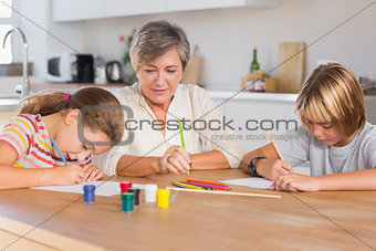 Granny and her grandchildren drawing seriously