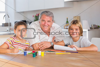 Grandfather and her grandchildren smiling at the camera with drawings