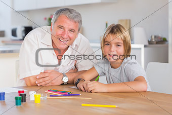 Grandfather and grandson looking at camera with drawings