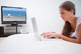 Woman on her laptop with television in the background