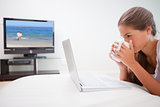 Woman taking a sip of coffee while surfing the internet in the living room