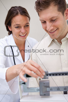 Doctor helping patient with adjusting scale