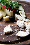 Splitting a solid tasty goat cheese with sesame seeds and herbs