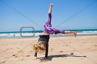 Young girl doing cartwheel at beach