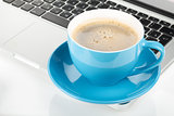 Blue coffee cup and laptop