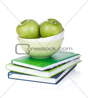 Green apples in fruit bowl and books