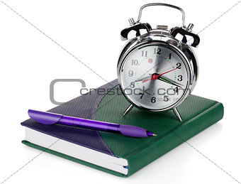 Alarm clock and pen on notepad