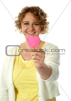 Woman showing pink paper heart to camera