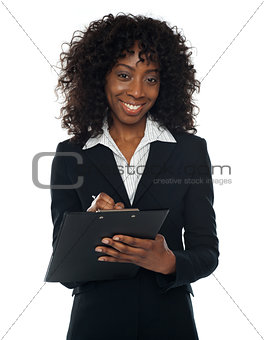 Pretty corporate woman writing on clipboard