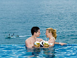 couple lovers swimming pool  seaside drinking coconut milk