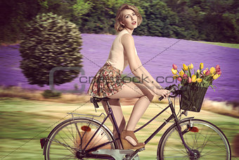 sexy blonde girl going on the bicycle on field