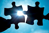 Hand holding two jigsaw pieces