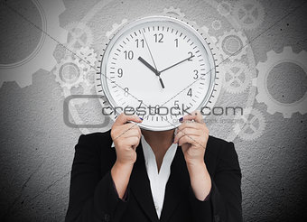 Businesswoman hiding her face with clock